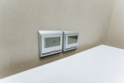 The room boasts a modern and chic look with two digital thermostats, a white counter, wood and metal accents, and hardwood floors, creating a stylish and contemporary design photo