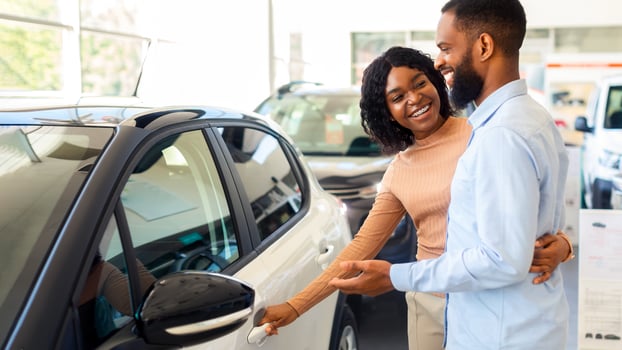 Car Choosing. Happy Black Spouses Standing Next To Modern Vehicle In Showroom, Cheerful African American Couple Purchasing New Automobile In Dealership Center, Discussing Auto Characteristics photo