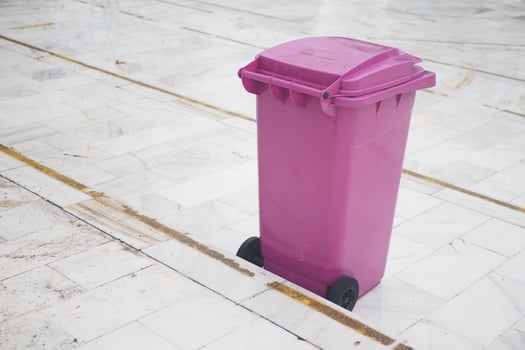 A Bright Pink Trash Bin is placed beautifully on a Marble Floor surface photo