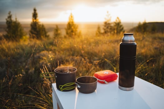 Experience the beauty of an outdoor cooking setup at sunset, complete with camping gear and a breathtaking scenic view around you photo