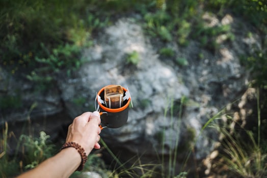 In the peaceful outdoors, find tranquility holding an enamel cup and leather wallet, surrounded by wild beauty. Enjoy nature while exploring the serene wilderness photo