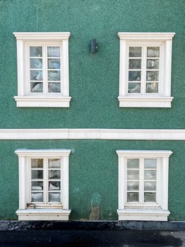 Three windows on a green building with white trim photo