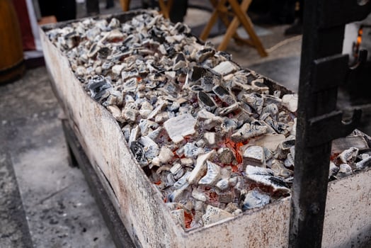On top of a wooden table, there is a substantial pile of charcoal that has been carefully placed, showcasing the contrast between the dark charcoal and the light wood surface underneath it photo