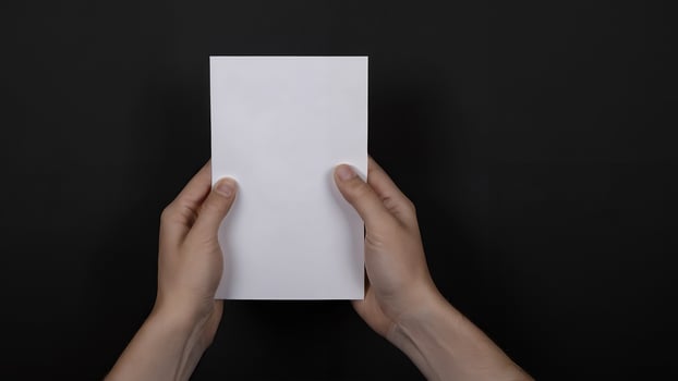 Hands holding blank white paper against black background. photo