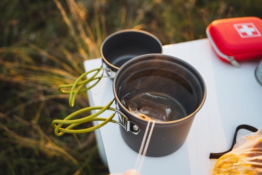 Outdoor cooking pots are beautifully arranged on a camp table, set against a stunning natural backdrop, perfect for exciting culinary adventures photo