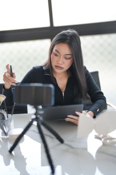 a woman sitting at a table with a tablet and a camera photo