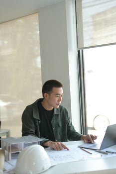 Architecture man sitting at a desk with a laptop photo