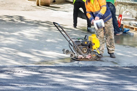 A road worker fills up a compactor tank to repair a road section by compacting fresh asphalt. Copy space. photo