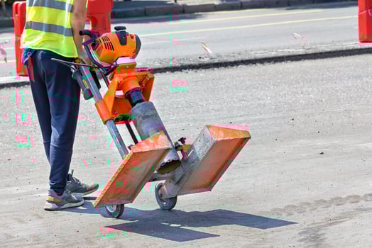 A road worker carries a powerful petrol drill to collect asphalt concrete samples. photo