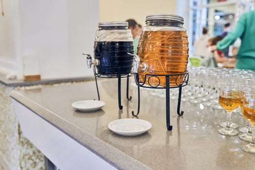 Juice from fresh fruits in the vending machine. Drinks are served on the table in a glass barrel with a tap. Drinks for catering at a party. photo