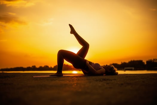 Woman practicing yoga in sunset. Setuasana, Half Bridge pose photo
