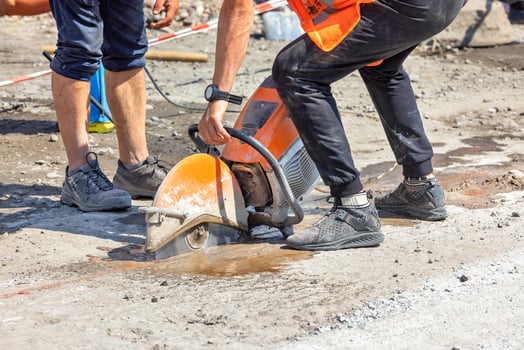 A worker cuts an old asphalt concrete pavement with a petrol circular cutter at the workplace on a sunny summer day. photo