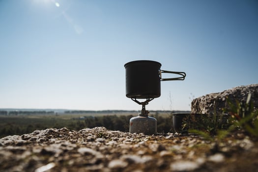 A cooking pot is sitting on top of a gas stove on a rocky hillside photo