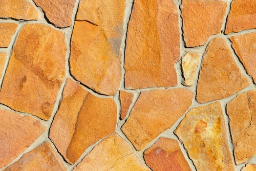 Texture of golden sandstone bricks in rough masonry wall. photo