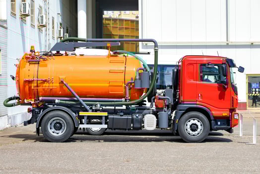 Modern orange and red sewage truck parked near industrial building. photo