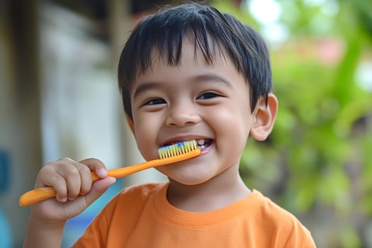 Happy child brushing teeth with orange toothbrush and smiling photo
