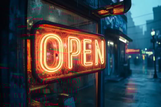 Bright neon open sign glowing on rainy city street at night photo