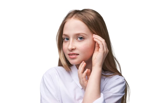 Caucasian young female with long blonde hair in white shirt touching face and smiling confidently. photo