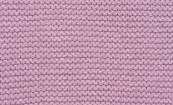 Knitted fabric made of pink wool threads, pigtail pattern, full frame. photo