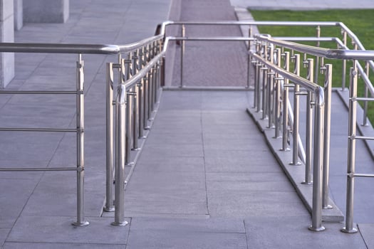 Modern accessibility ramp with stainless steel railings on sidewalk outdoor urban environment. photo