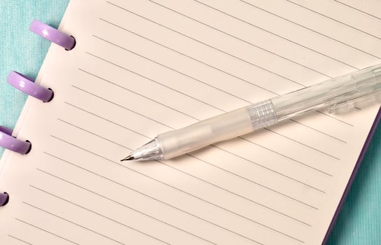 Close up cropped note book with white lined paper and mechanical pencil isolated on horizontal light blue background. photo