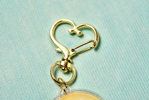 Key chain heart shaped metal ring hook clip isolated on horizontal light blue background. photo