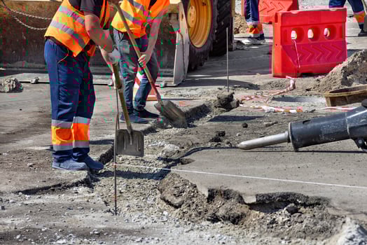 Construction workers repairing pavement in a busy urban area during daylight hours photo