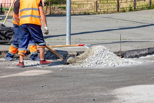 Workers skillfully repair a city street with fresh concrete on a sunny day. Copy space. photo