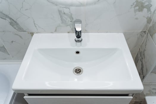 A white sink sitting in a bathroom with a white toilet photo