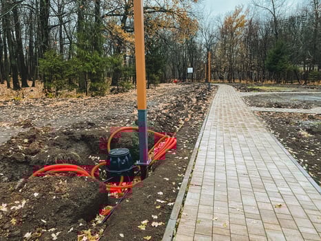 In a tranquil and peaceful park, a stunningly beautiful brick walkway gracefully weaves through the lush landscape, complemented by a rustic pole situated in the nearby dirt area photo