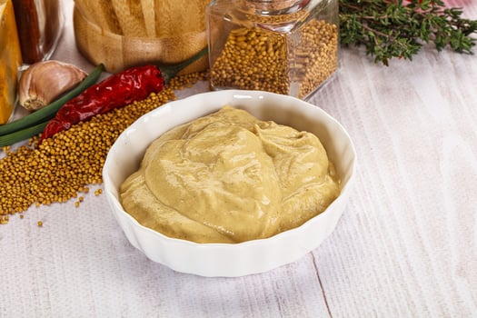 A bowl of mustard next to a bowl of spices photo