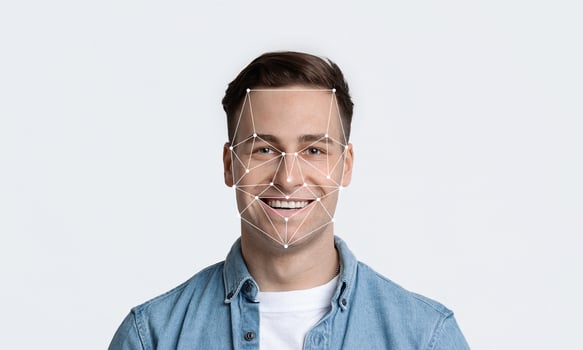 Smiling young man is featured against a plain background, demonstrating facial recognition technology with geometric lines outlining his face, emphasizing identification capabilities. photo