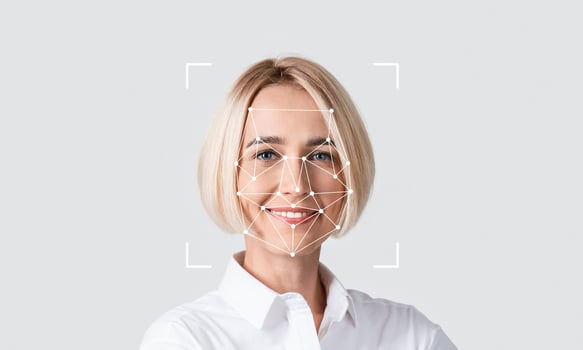 A woman smiles confidently while demonstrating facial recognition technology. The digital overlay highlights key facial features for identification purposes. photo