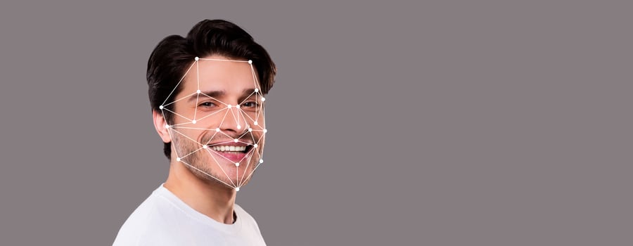 A smiling man is highlighted with facial recognition technology. Geometric lines overlay his features, demonstrating identification capabilities against a neutral background. photo