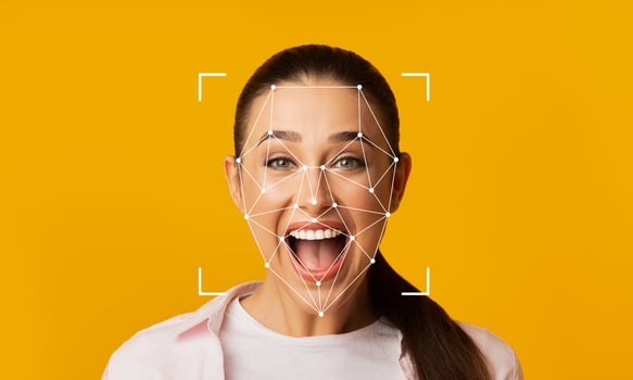A woman expresses joy with a wide smile, while facial recognition technology identifies her features. The bright yellow background enhances the focus on her facial expressions. photo