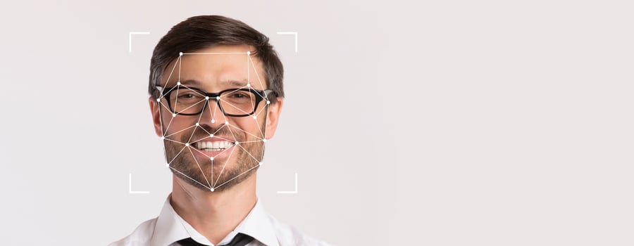 A smiling man with glasses is featured prominently on a blank background, highlighting facial recognition technology. His expression conveys friendliness in a professional context. photo
