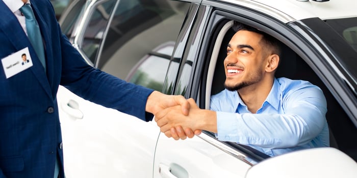 Happy middle-eastern man sitting in white luxury car shaking sales manager hand and smiling, celebrating successful deal. Closeup of arab guy buying brand new comfortable auto in showroom photo