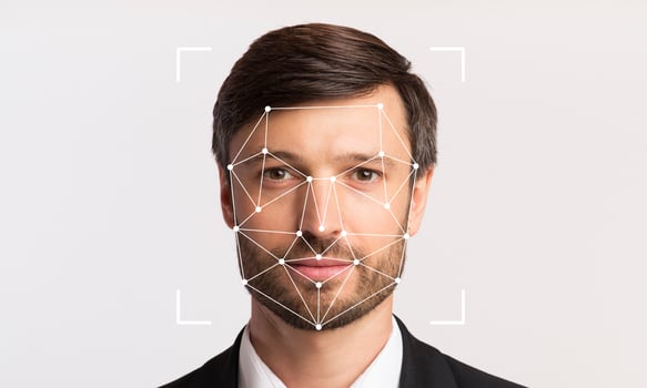 A man in formal attire is positioned against a neutral background, with facial recognition markers overlaid on his face. The technology highlights individual identification capabilities. photo