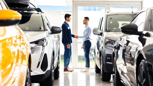 Middle-eastern young man customer and sales assistant shaking hands, car showroom interior, friendly manager greeting wealthy arab guy, standing among luxury brand new autos, full size shot photo