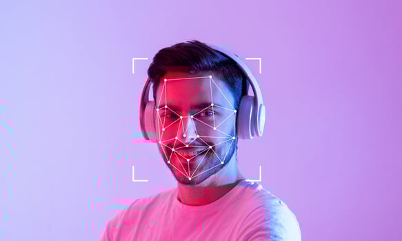 A young person is wearing headphones while participating in facial recognition technology. The vibrant background highlights the individual's cheerful expression and modern tech setup. photo