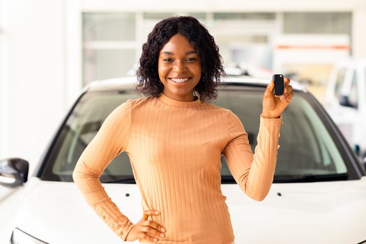 Portrait Of Happy African American Woman Holding Keys Of Her New Car After Buying Automobile In Modern Dealership Center, Excited Black Female Standing Near Luxury Vehicle And Smiling At Camera photo