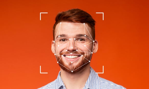 A young man smiles confidently while facial recognition technology scans his features against an orange background. The high-tech identification is evident and illustrative of modern advancements. photo