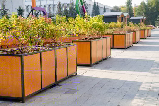 The bustling sidewalk is adorned with beautiful wooden planters overflowing with vibrant plants and colorful flowers, bringing a refreshing touch of nature to the urban landscape photo