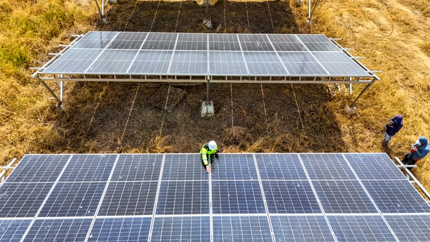 Two workers in safety gear performing maintenance under solar panels in a field, h ighlighting renewable energy, sustainability, and the efficient management of solar power systems in natural settings photo