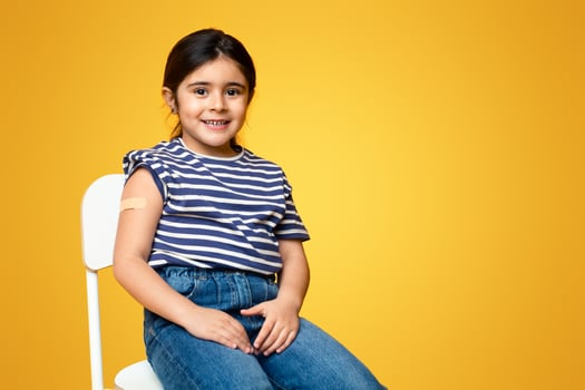 Cute Vaccinated Little Girl Showing Arm With Adhesive Bandage After Injection Shot, Smiling Preteen Female Child Posing On Yellow Background After Getting Coronavirus Vaccination, Copy Space photo