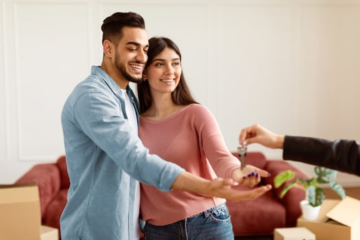 Buying New Apartment. Portrait of happy smiling couple taking key of future new house. Professional real estate agent holding in hand and giving keys to young millennial buyers. Mortgage Concept photo