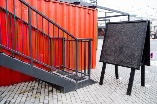 In front of a striking red staircase, there is a prominent black sign positioned right beside it, drawing attention to both the structure and its accompanying information photo