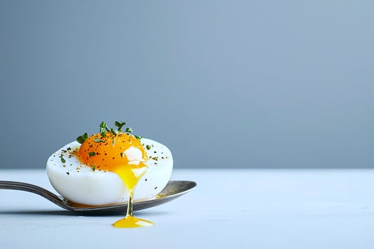 A soft boiled organic egg with golden yolk dripping onto a vintage spoon, perfect for gourmet nutrition photo
