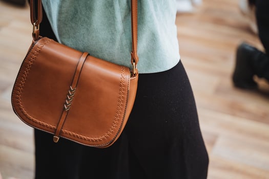She is stylishly carrying a brown leather shoulder bag photo