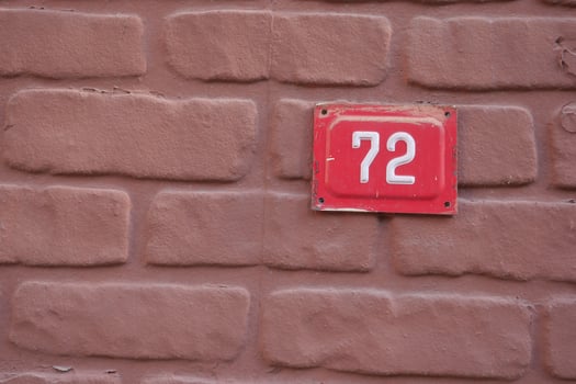 The number 72 stands out on a Red Tile against a Brown Brick Wall photo
